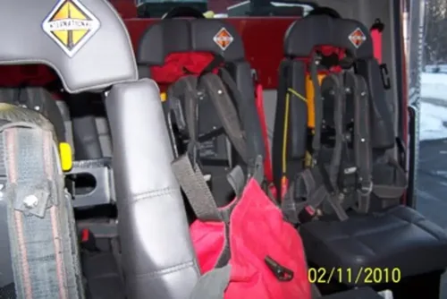 Exterior view of small fire truck showing cab, body compartments, and wheel/tire area.