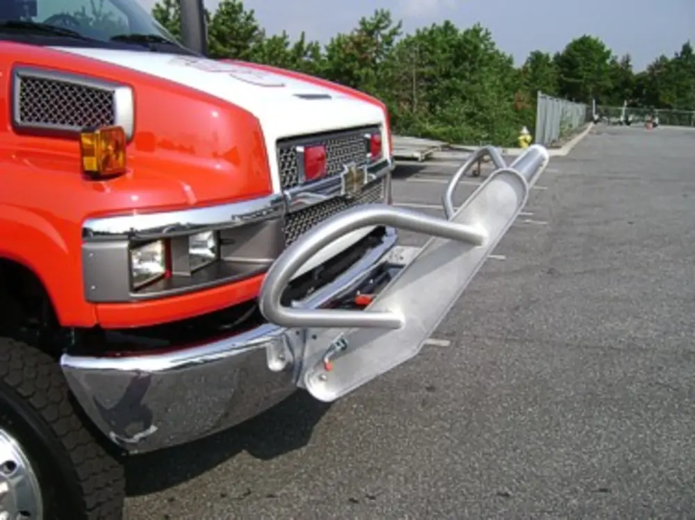 Exterior view of small fire truck showing cab, body compartments, and wheel/tire area.