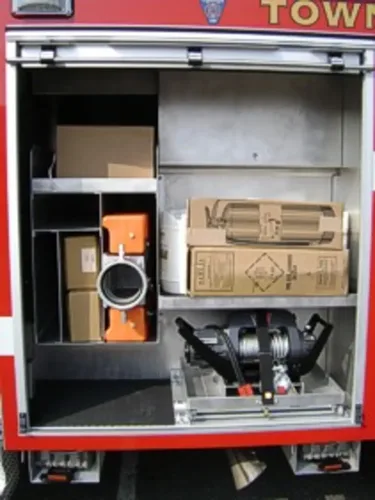 Exterior view of small fire truck showing cab, body compartments, and wheel/tire area.