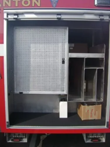 Exterior view of small fire truck showing cab, body compartments, and wheel/tire area.