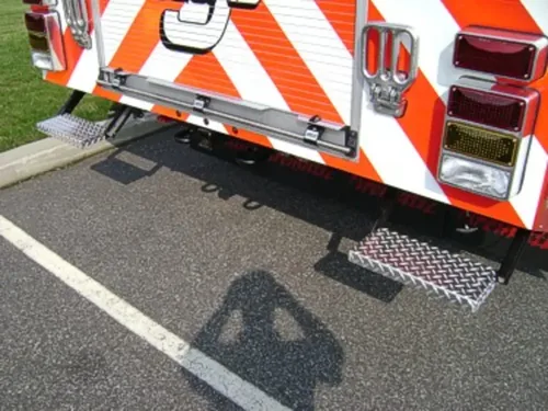 Exterior view of small fire truck showing cab, body compartments, and wheel/tire area.