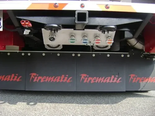 Exterior view of small fire truck showing cab, body compartments, and wheel/tire area.