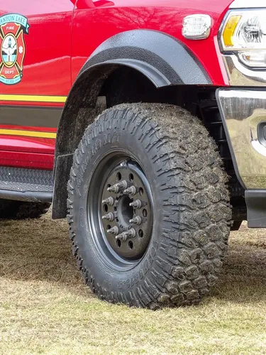Exterior view of small fire truck showing cab, body compartments, and wheel/tire area.