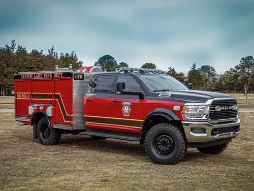 Exterior view of small fire truck showing cab, body compartments, and wheel/tire area.