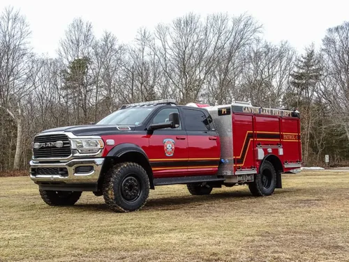Exterior view of small fire truck showing cab, body compartments, and wheel/tire area.
