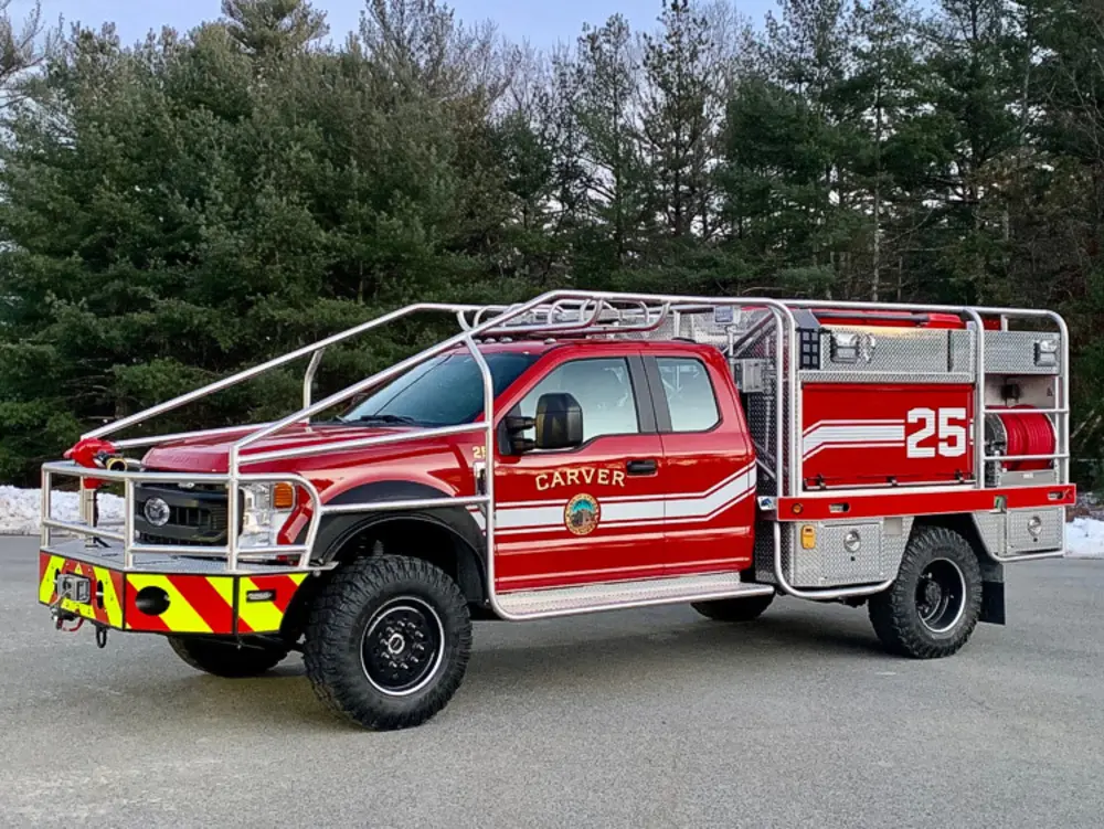 Exterior view of small fire truck showing cab, body compartments, and wheel/tire area.
