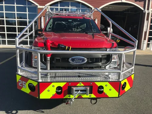 Exterior view of small fire truck showing cab, body compartments, and wheel/tire area.