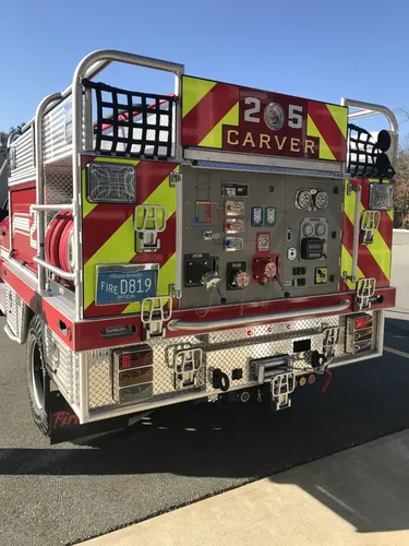 Exterior view of small fire truck showing cab, body compartments, and wheel/tire area.