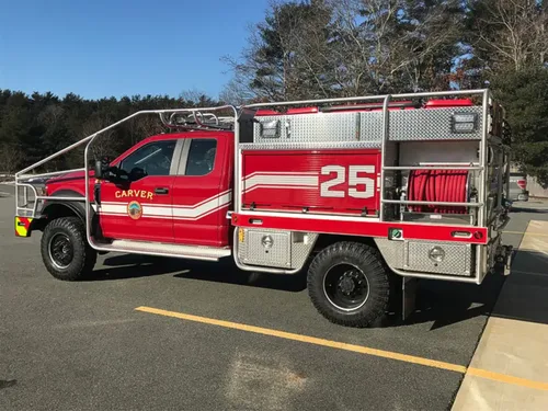 Exterior view of small fire truck showing cab, body compartments, and wheel/tire area.