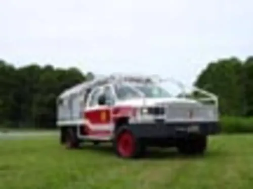 Exterior view of small fire truck showing cab, body compartments, and wheel/tire area.