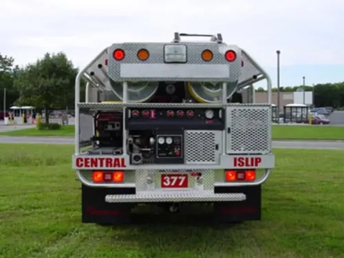 Exterior view of small fire truck showing cab, body compartments, and wheel/tire area.