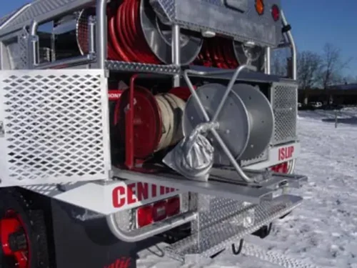 Exterior view of small fire truck showing cab, body compartments, and wheel/tire area.