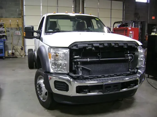 Exterior view of small fire truck showing cab, body compartments, and wheel/tire area.