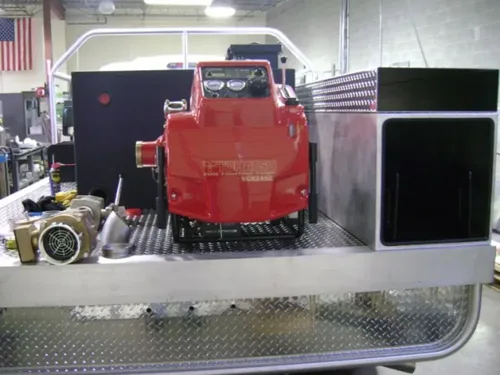 Exterior view of small fire truck showing cab, body compartments, and wheel/tire area.