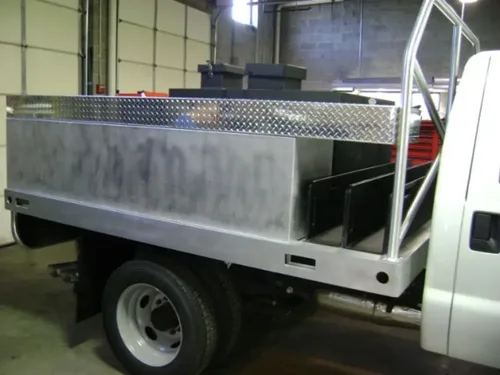 Exterior view of small fire truck showing cab, body compartments, and wheel/tire area.