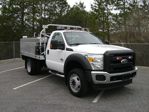 Exterior view of small fire truck showing cab, body compartments, and wheel/tire area.