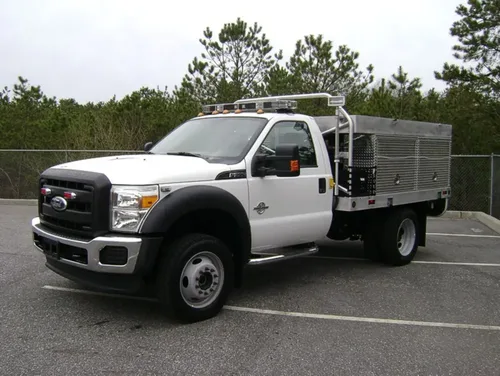 Exterior view of small fire truck showing cab, body compartments, and wheel/tire area.