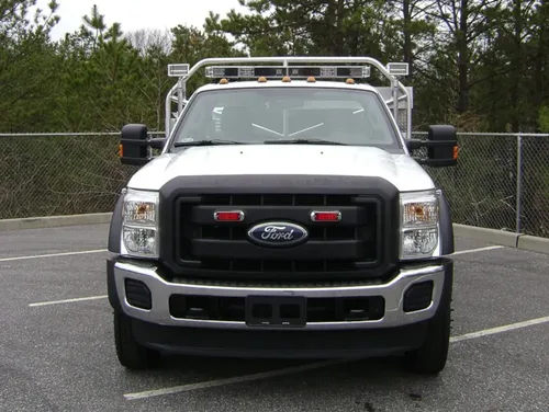 Exterior view of small fire truck showing cab, body compartments, and wheel/tire area.