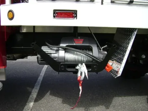 Exterior view of small fire truck showing cab, body compartments, and wheel/tire area.
