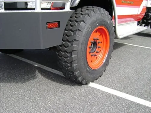 Exterior view of small fire truck showing cab, body compartments, and wheel/tire area.