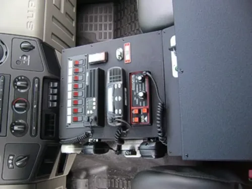 Exterior view of small fire truck showing cab, body compartments, and wheel/tire area.