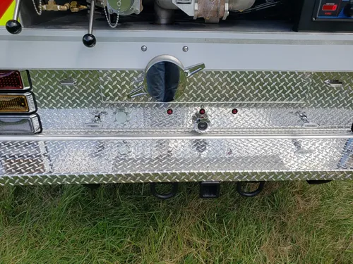 Exterior view of small fire truck showing cab, body compartments, and wheel/tire area.