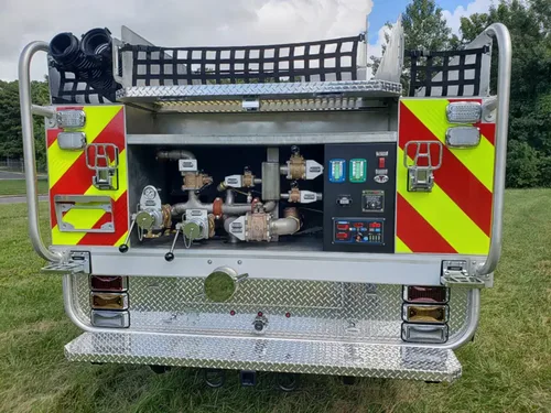 Exterior view of small fire truck showing cab, body compartments, and wheel/tire area.
