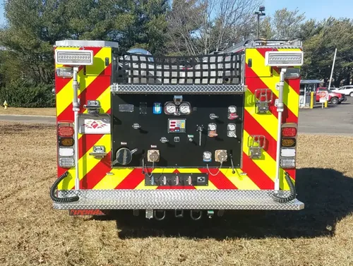 Exterior view of small fire truck showing cab, body compartments, and wheel/tire area.