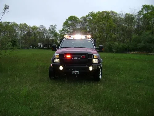 Exterior view of small fire truck showing cab, body compartments, and wheel/tire area.