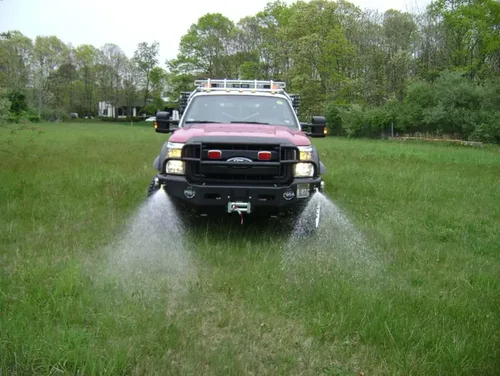 Exterior view of small fire truck showing cab, body compartments, and wheel/tire area.