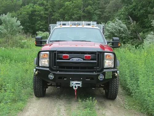 Exterior view of small fire truck showing cab, body compartments, and wheel/tire area.