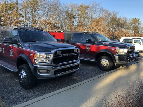 Exterior view of small fire truck showing cab, body compartments, and wheel/tire area.