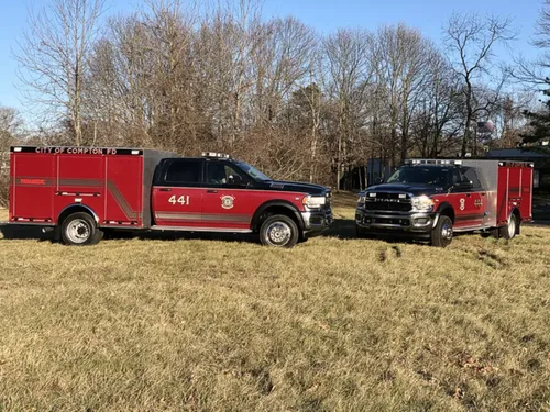 Exterior view of small fire truck showing cab, body compartments, and wheel/tire area.