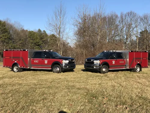Exterior view of small fire truck showing cab, body compartments, and wheel/tire area.