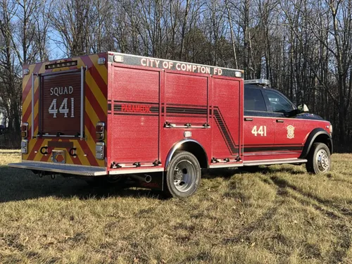 Exterior view of small fire truck showing cab, body compartments, and wheel/tire area.