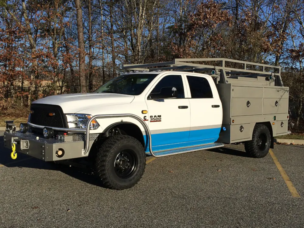 Exterior view of small fire truck showing cab, body compartments, and wheel/tire area.