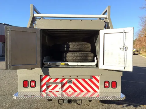Exterior view of small fire truck showing cab, body compartments, and wheel/tire area.