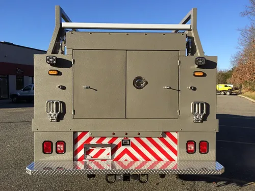 Exterior view of small fire truck showing cab, body compartments, and wheel/tire area.