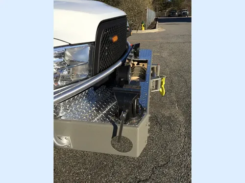 Exterior view of small fire truck showing cab, body compartments, and wheel/tire area.