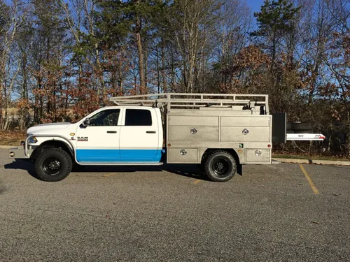 Exterior view of small fire truck showing cab, body compartments, and wheel/tire area.