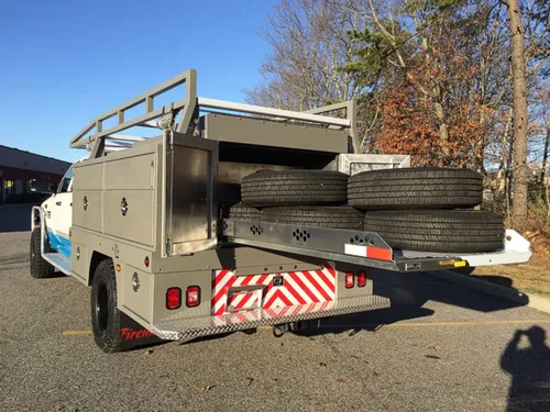 Exterior view of small fire truck showing cab, body compartments, and wheel/tire area.