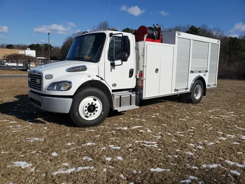 Exterior view of small fire truck showing cab, body compartments, and wheel/tire area.