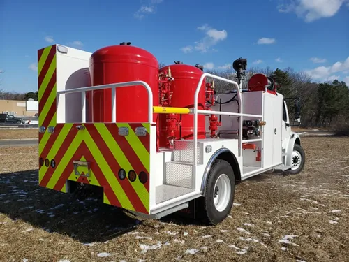 Exterior view of small fire truck showing cab, body compartments, and wheel/tire area.