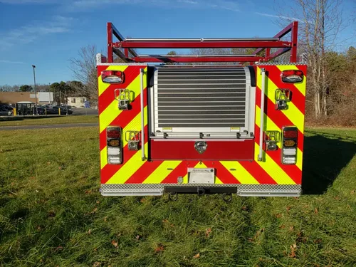 Exterior view of small fire truck showing cab, body compartments, and wheel/tire area.