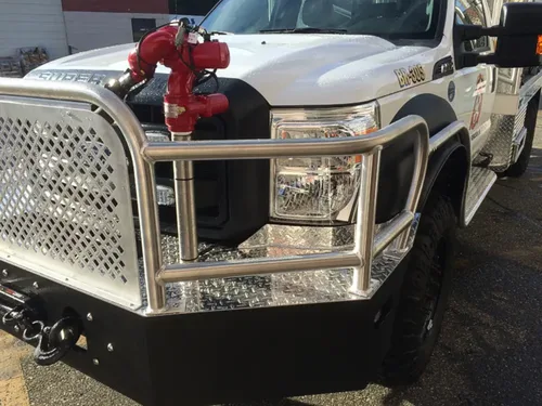 Exterior view of small fire truck showing cab, body compartments, and wheel/tire area.