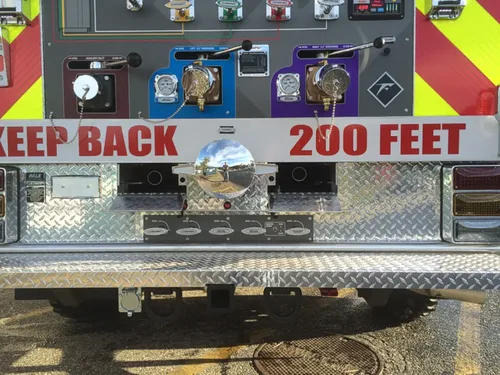 Exterior view of small fire truck showing cab, body compartments, and wheel/tire area.