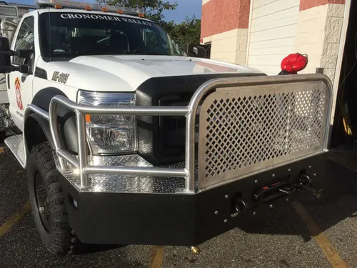 Exterior view of small fire truck showing cab, body compartments, and wheel/tire area.
