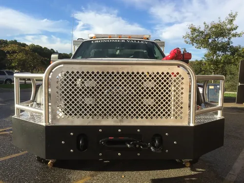 Exterior view of small fire truck showing cab, body compartments, and wheel/tire area.