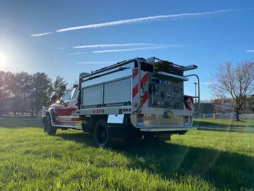Exterior view of small fire truck showing cab, body compartments, and wheel/tire area.