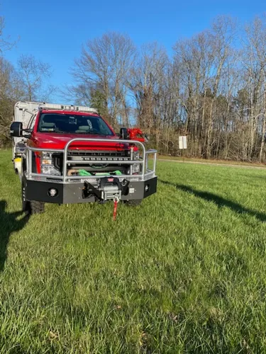 Exterior view of small fire truck showing cab, body compartments, and wheel/tire area.
